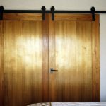 Elegant master bedroom with brushed gold sliding barn door kit on large wooden door