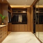 Luxurious walk-in closet featuring floor-to-ceiling mirrored bypass sliding doors with brass hardware