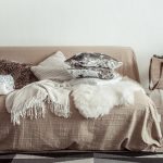 Styled sofa with layered throw pillows in various textures and neutral color palette