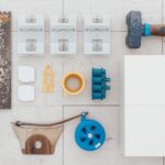 A complete set of tile installation tools laid out on a clean subfloor, including a notched trowel, tile spacers, rubber mallet, grout float, chalk line, and porcelain tiles.