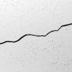 Close-up of a hairline crack in a painted interior wall.