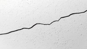 Close-up of a hairline crack in a painted interior wall.