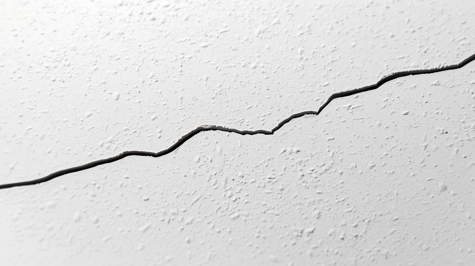 Close-up of a hairline crack in a painted interior wall.
