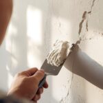 Homeowner applying joint compound to repair a drywall crack.
