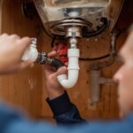 Image 1_ Homeowner inspecting pipes under sink for leaks
