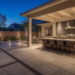 Modern 2026 patio design with large format concrete pavers, built-in outdoor kitchen, pergola and ambient lighting