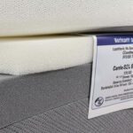 A close-up photo of high-density foam layers or a warranty certificatelabel on a mattress.