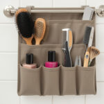 An over-the-door bathroom organizer with small pockets holding hairbrushes, nail polish, and grooming tools.