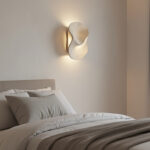 Sculptural wall sconce lighting fixture beside a bed