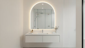 backlit arched LED mirror above a floating vanity, reflecting a frameless glass shower in a bright, minimalist bathroom.